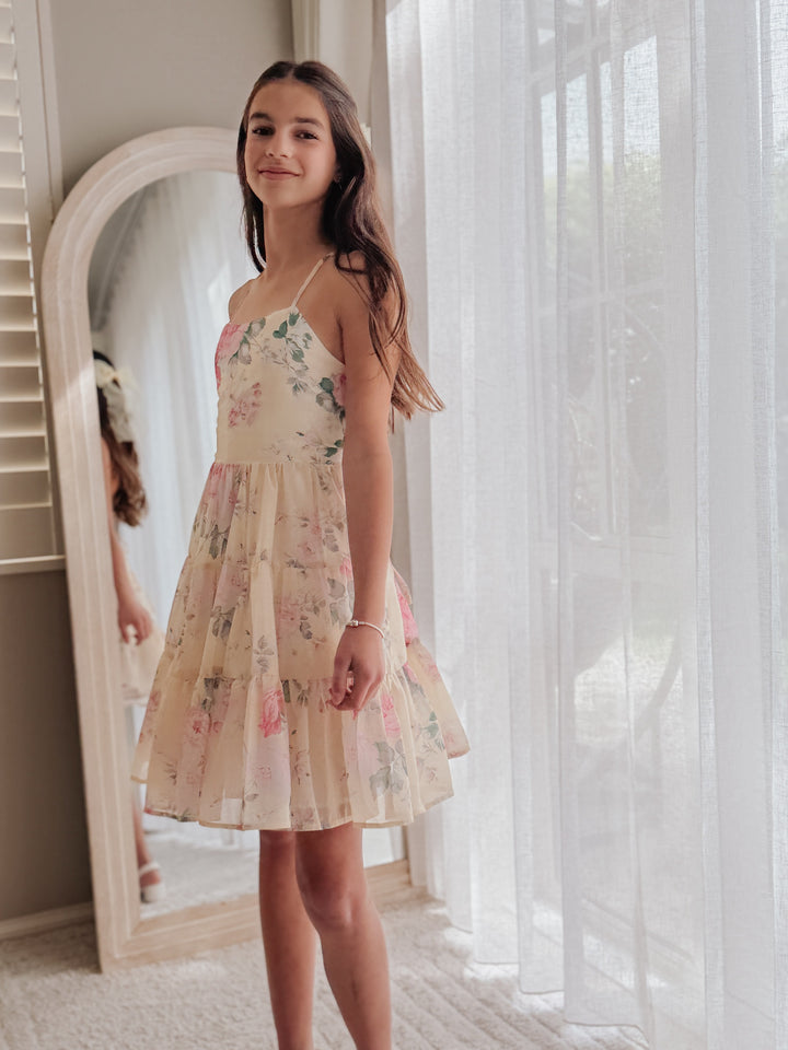 Phoebe Yellow Rose girls chiffon dress on a model, front three-quarter view showing the pink rose print and tiered skirt