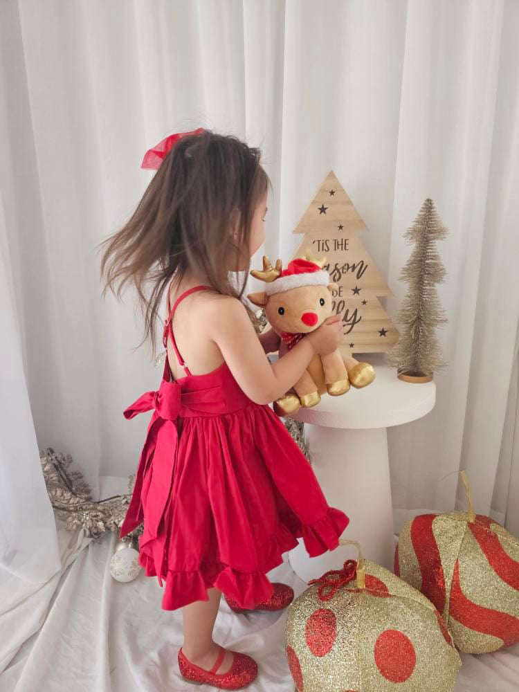 Girl smiling in bright red holiday dress with bow for Christmas family portrait