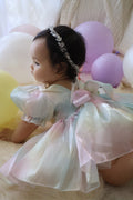 Baby sitting for milestone photos in puff-sleeve rainbow organza romper, true-to-size fit