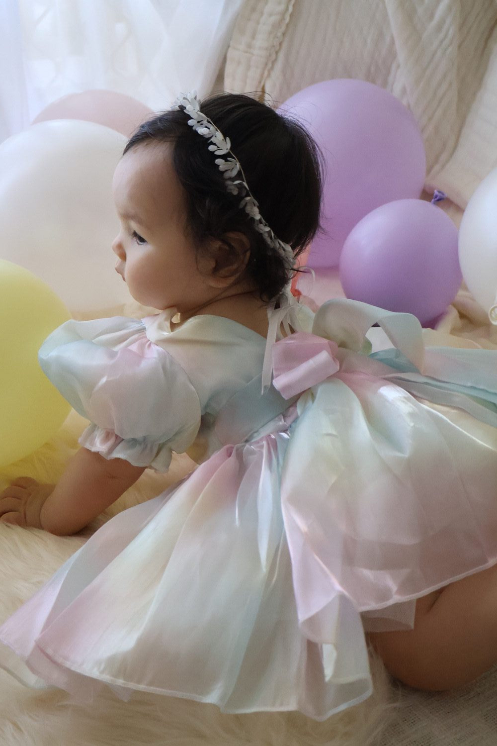 Baby sitting for milestone photos in puff-sleeve rainbow organza romper, true-to-size fit
