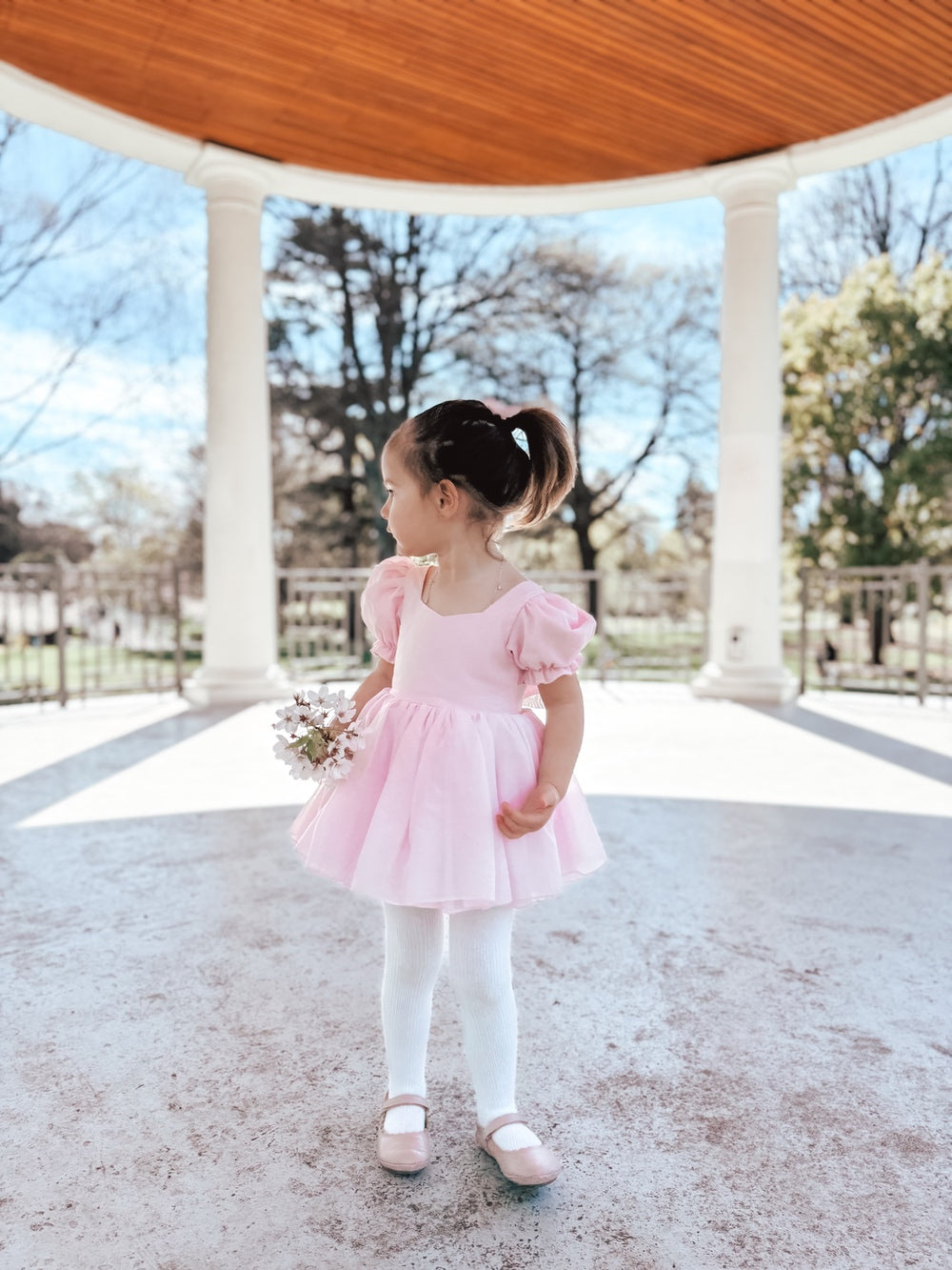 Baby girl wearing Arabella baby pink dress romper front-facing with puff sleeves