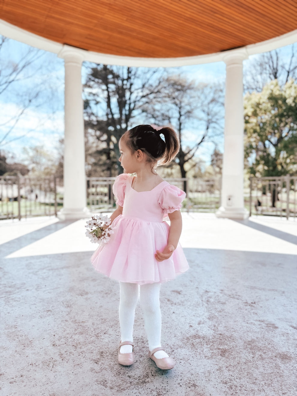 Baby girl wearing Arabella baby pink dress romper front-facing with puff sleeves