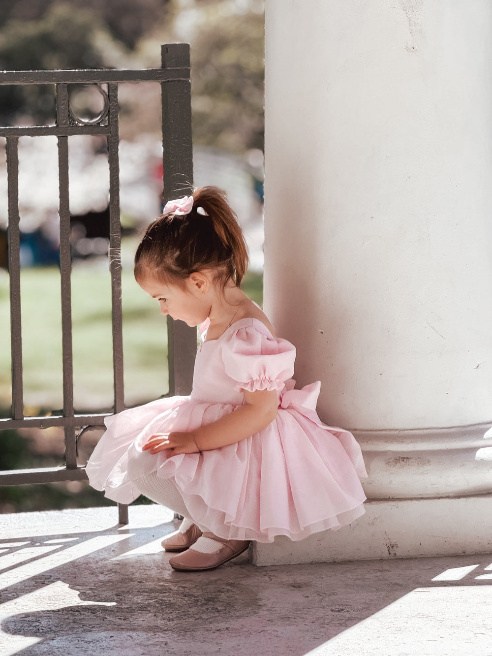Girls pink romper dress showing pleated skirt and puff sleeve