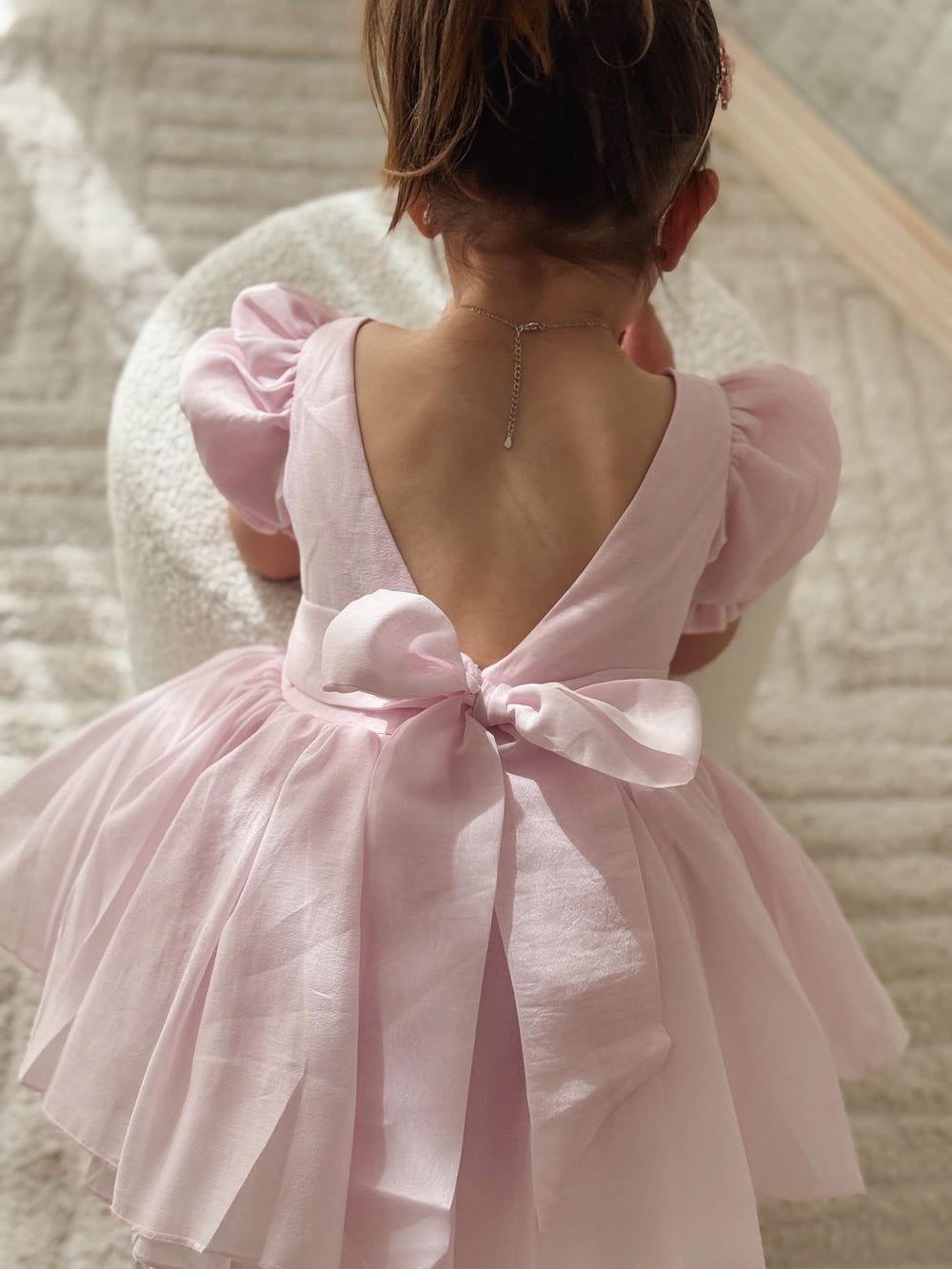 Girl wearing Arabella pink dress standing in soft natural light