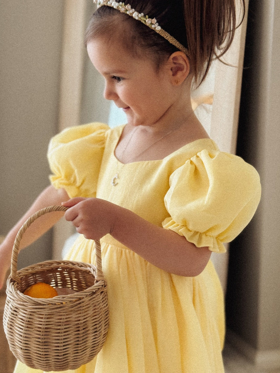 Baby girl wearing Arabella yellow romper with puff sleeves and bow