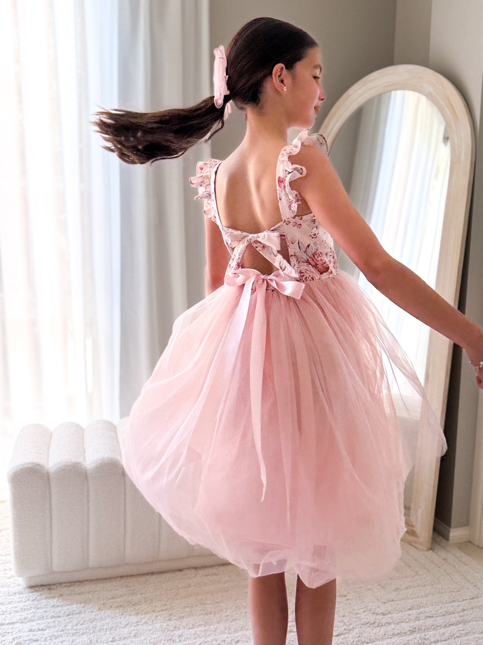 Tween girl twirling in dusty pink tulle party dress for wedding or birthday