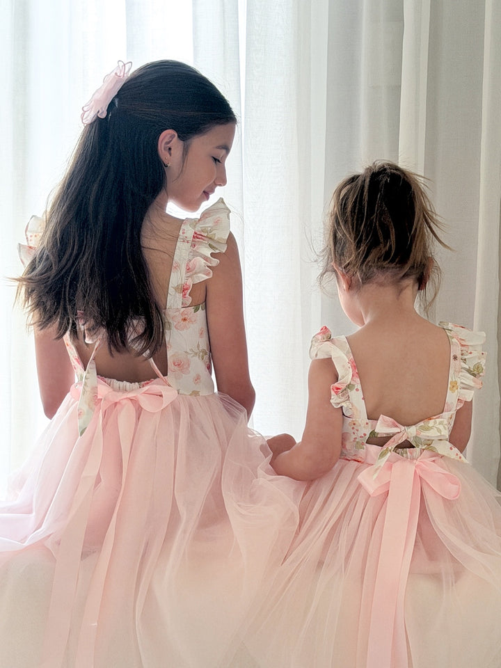 Close-up of light pink girls tulle dress with floral top and ruffle shoulders