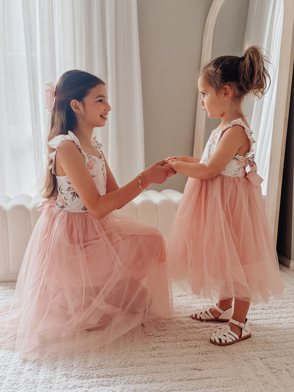 Close-up of white bodice with dusty pink floral embroidery on girls’ dress