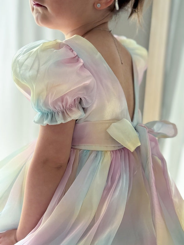 Young girl sitting in rainbow dress with skirt spread in a circle
