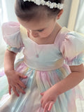 Seated pose showing organza layers and puff sleeves in rainbow fabric