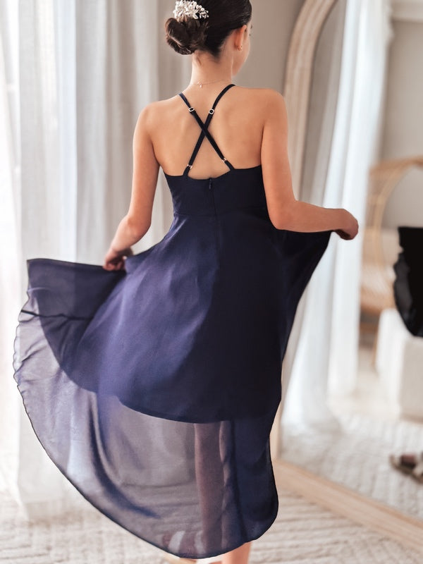 Girl twirling in navy blue hi-low dress with flowy layers