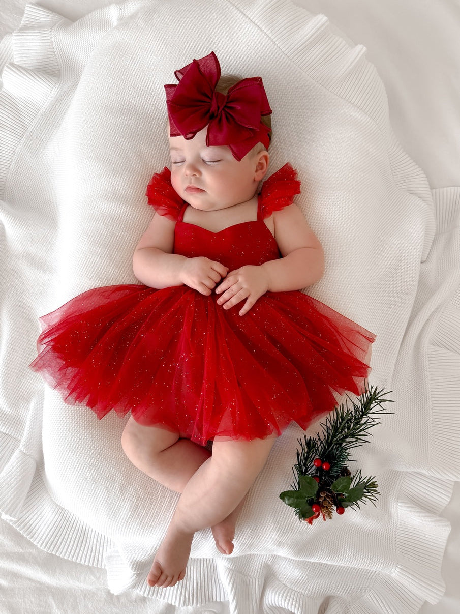 Baby girl wearing red sparkly Christmas tutu dress with frill sleeves