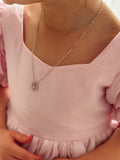 Close-up of silver necklace featuring pink flower charm