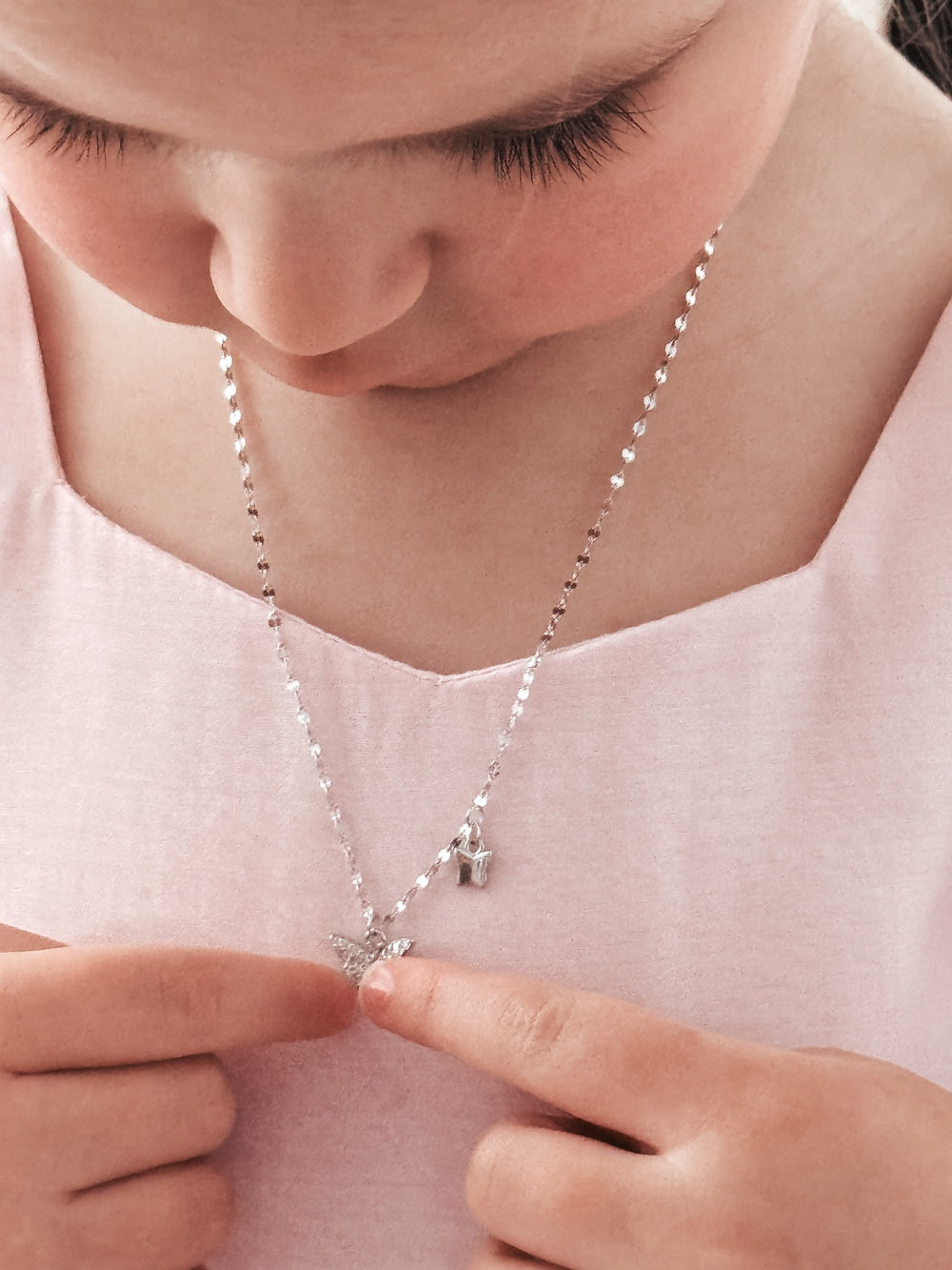Detail shot of butterfly charms on girls silver necklace