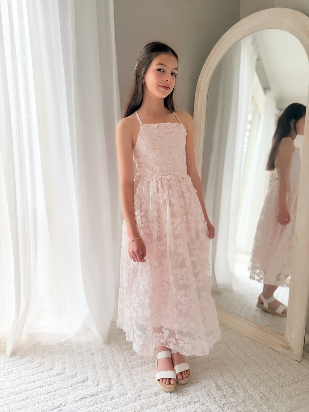 Girl standing in Clarissa Girls Light Pink Dress – flowing skirt and embroidered floral texture
