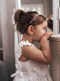 Baby wearing soft white flower girl dress for wedding or christening