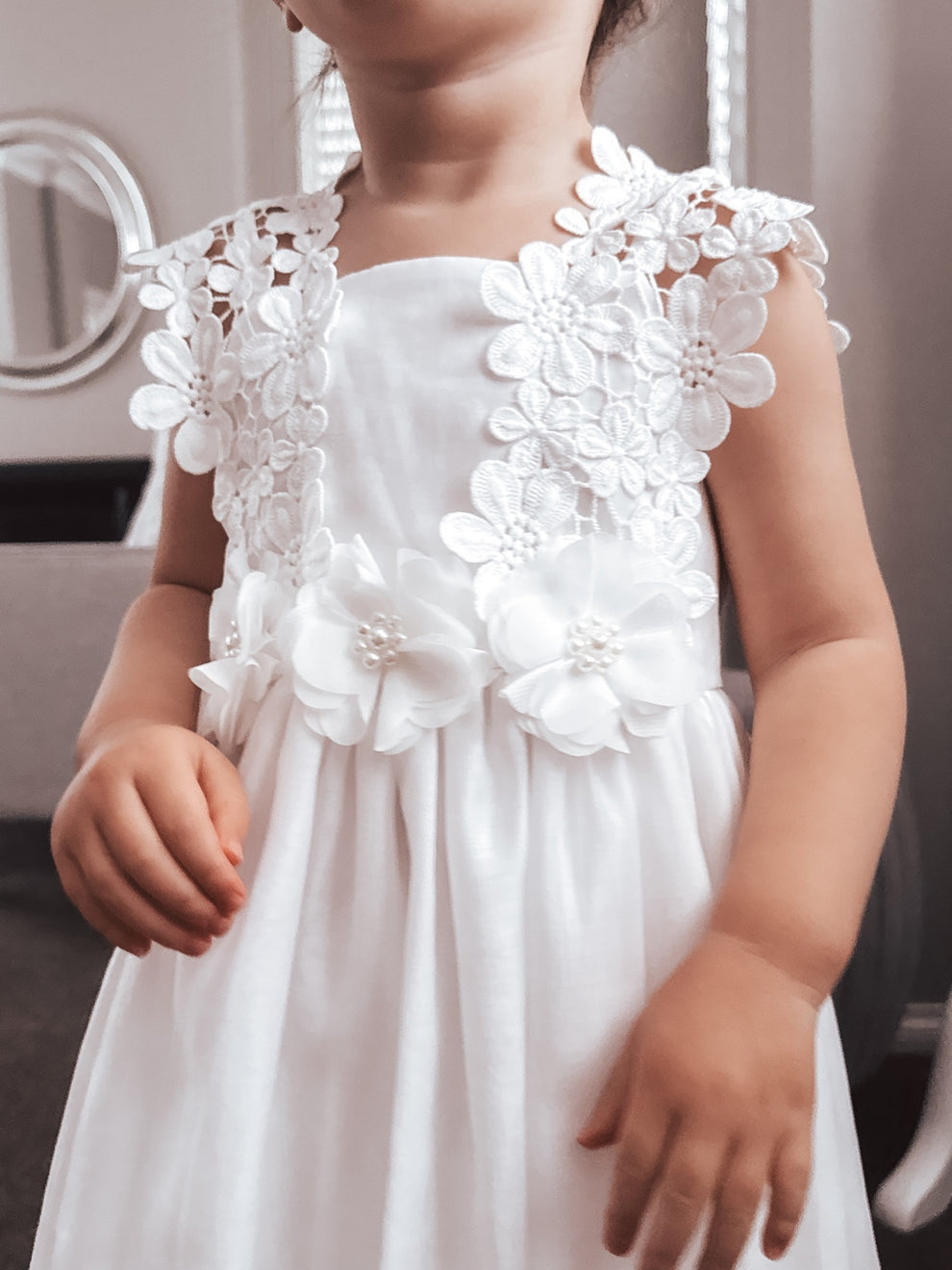 Close-up of pearl and tulle flower details on white flower girl dress