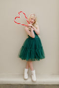 Girl wearing the Juniper green Christmas dress with a tiered tulle skirt, holding candy canes.