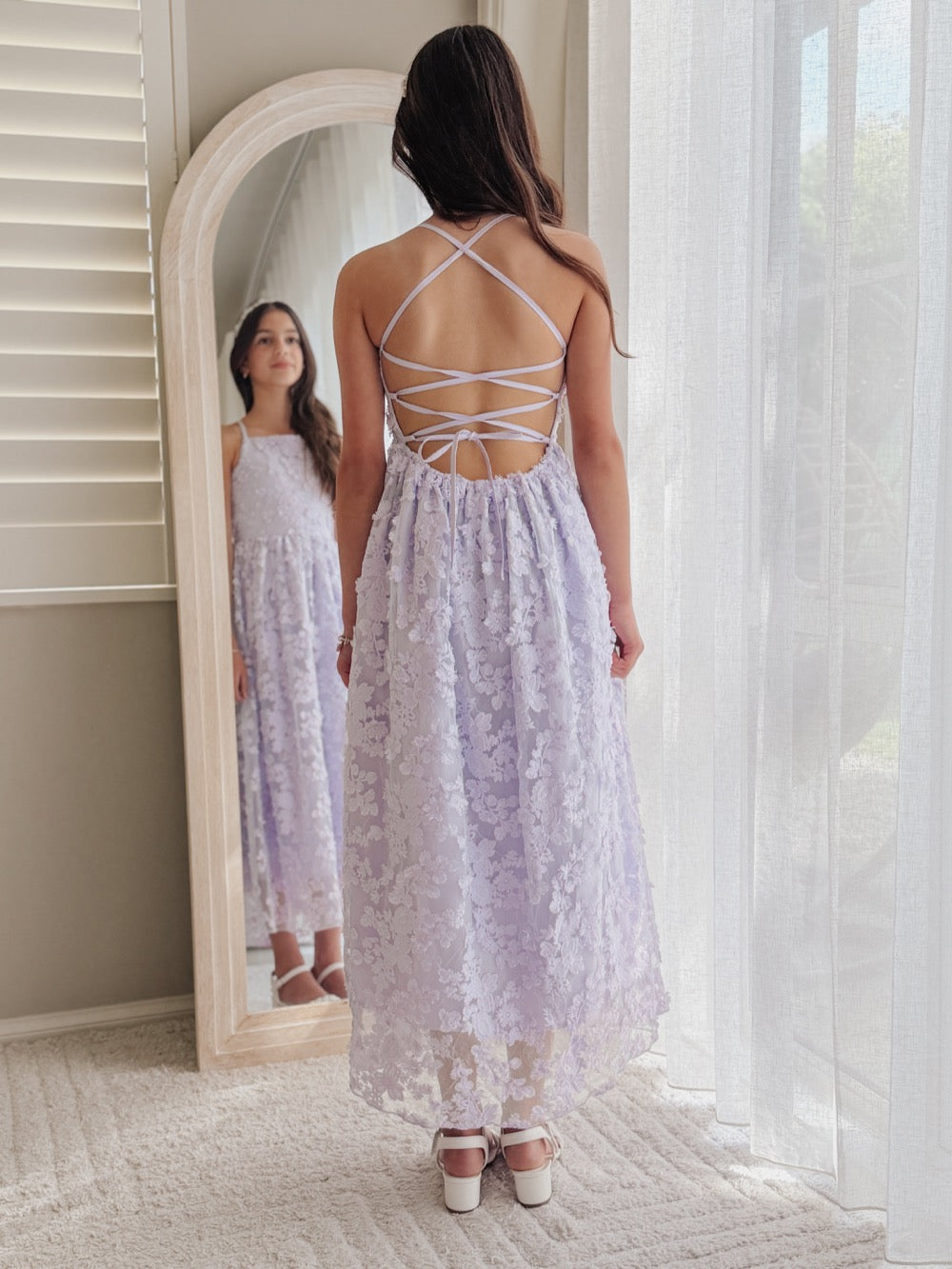 Clarissa lilac 3D flower girl dress, full-length back view showing lace-up straps beside a mirror.