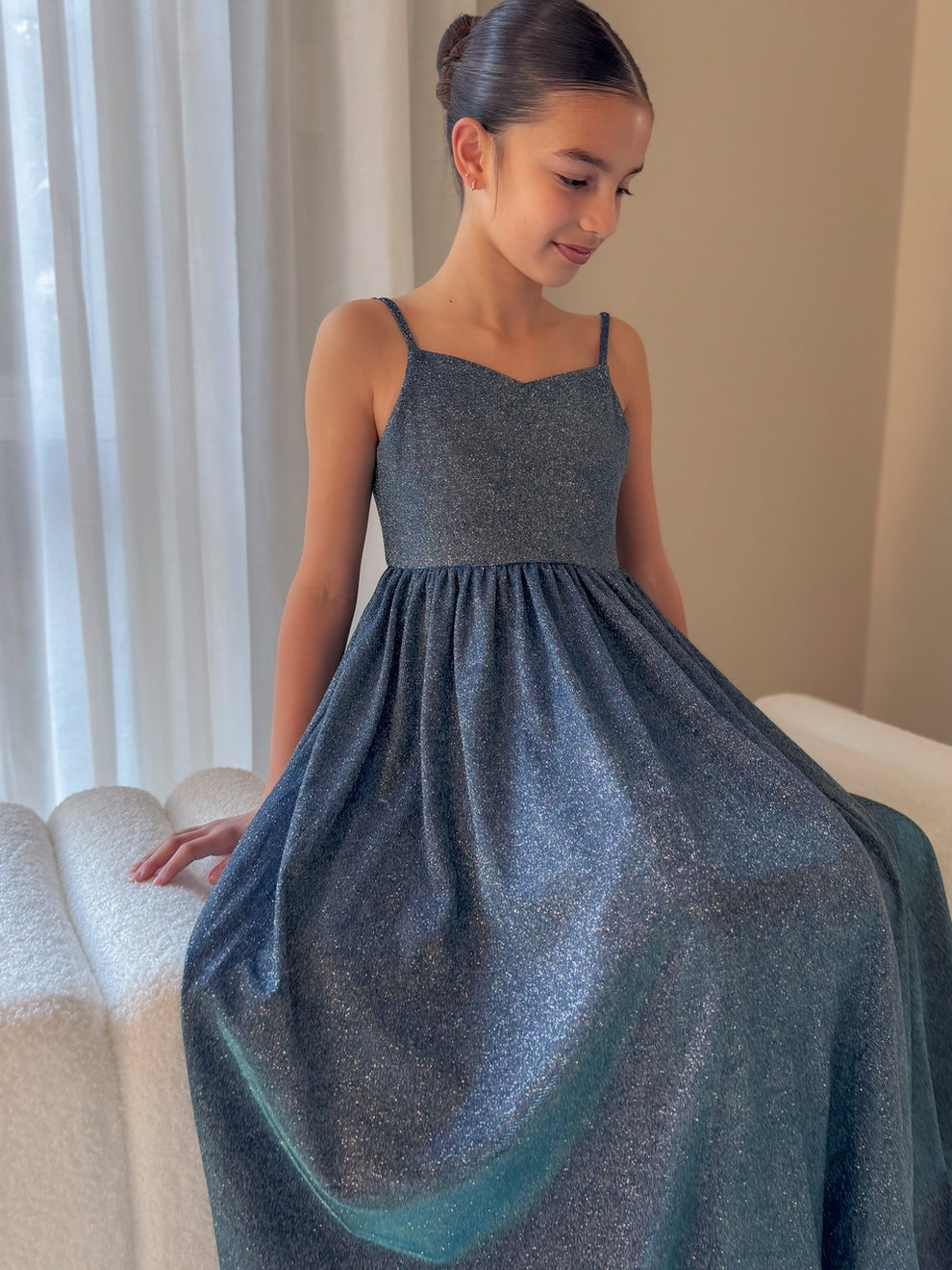 Claudia blue-green girls formal dress with shimmering skirt, seated view.
