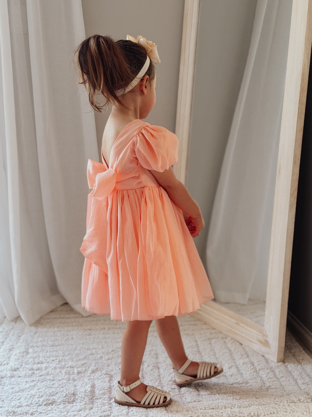 Peach girls special occasion dress with shimmer fabric and statement bow on the back.