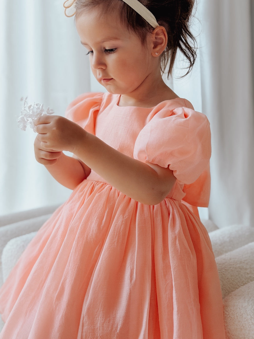 Girls peach formal dress with shimmering fabric and tied bow at the back.