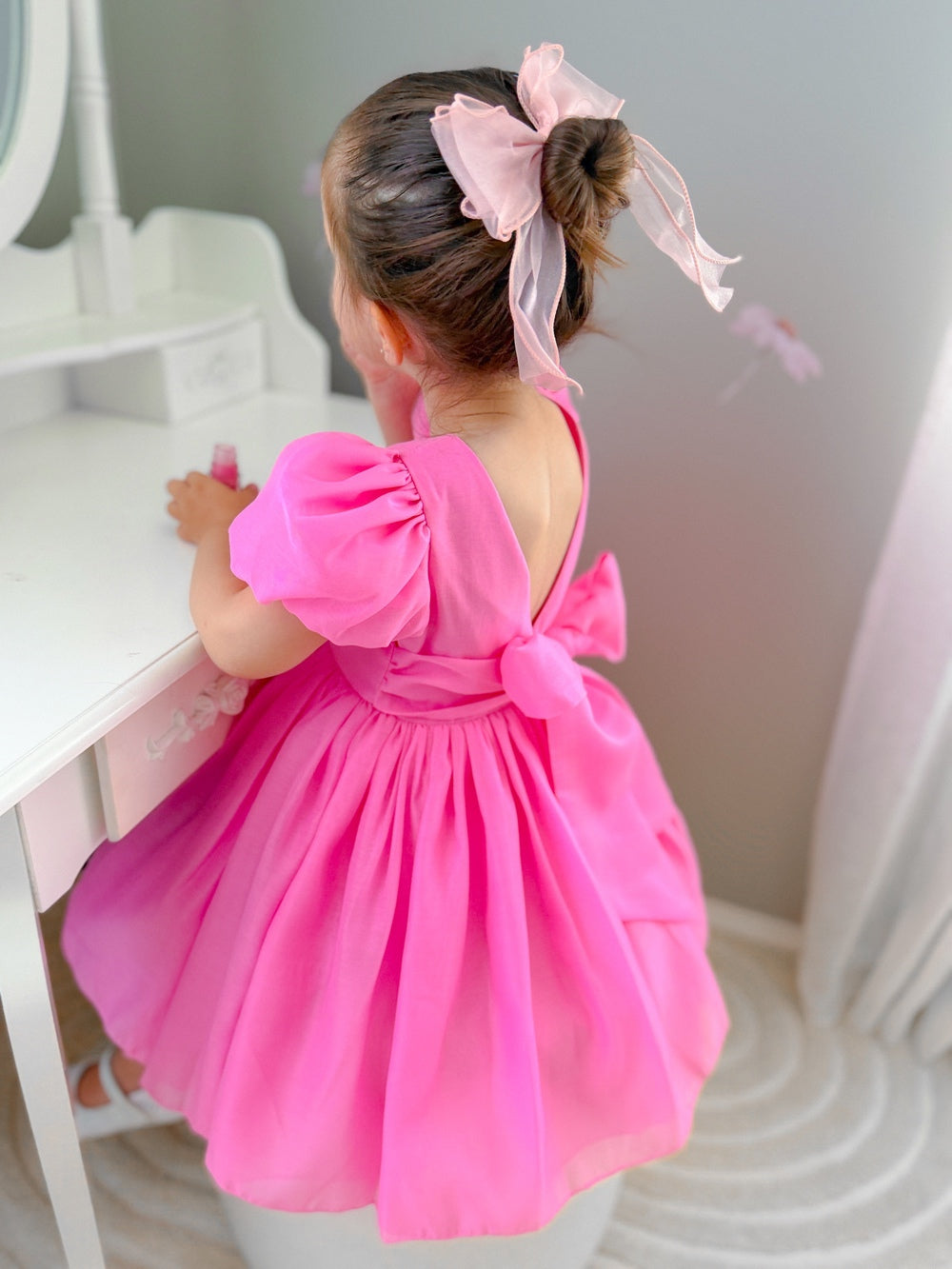 Below-knee hot pink girls party dress with puff sleeves and statement back bow