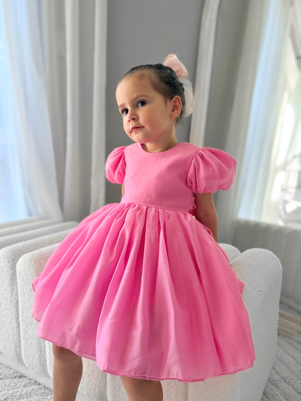 Flower girl wearing bright hot pink dress with elegant V-back and bow
