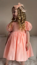 Close-up of peach V-back bow on Delia Girls Dress — perfect wedding and event dress