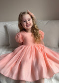 Delia Peach Dress twirling shot — below-knee skirt and puff sleeves for special occasions