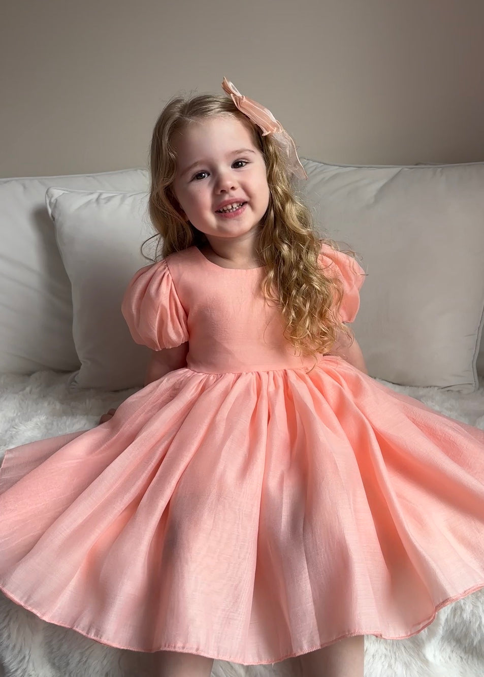 Delia Peach Dress twirling shot — below-knee skirt and puff sleeves for special occasions