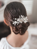 A silver flower hair clip adorned with diamante stones, worn in a floral arrangement on a woman's updo hairstyle.