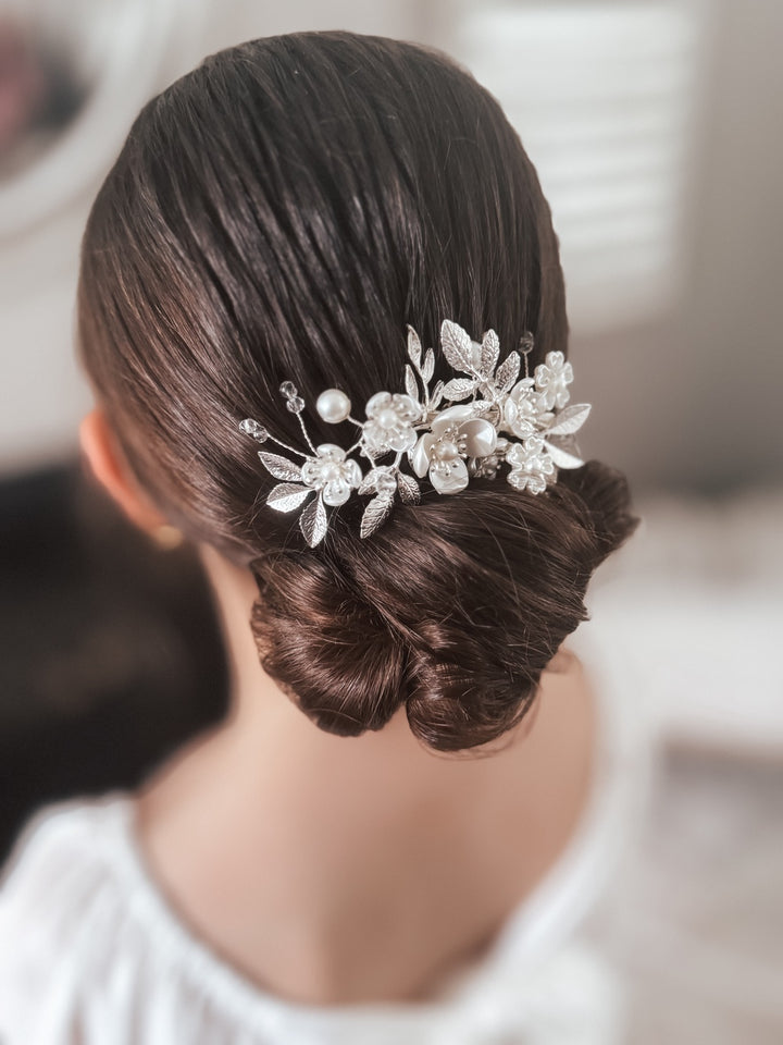 A silver flower hair clip adorned with diamante stones, worn in a floral arrangement on a woman's updo hairstyle.