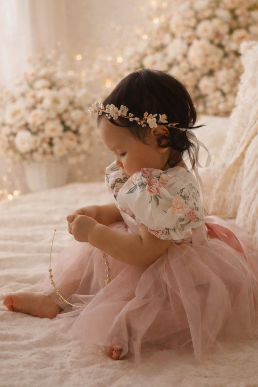Child in a floral dress sitting on a bed with floral decorations in the background