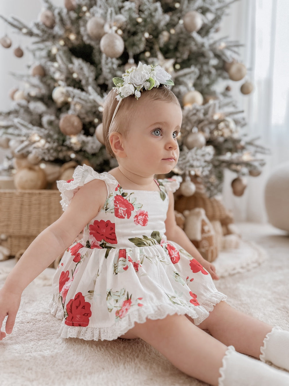 Baby wearing Faith Floral Christmas Romper playing under twinkling Christmas lights