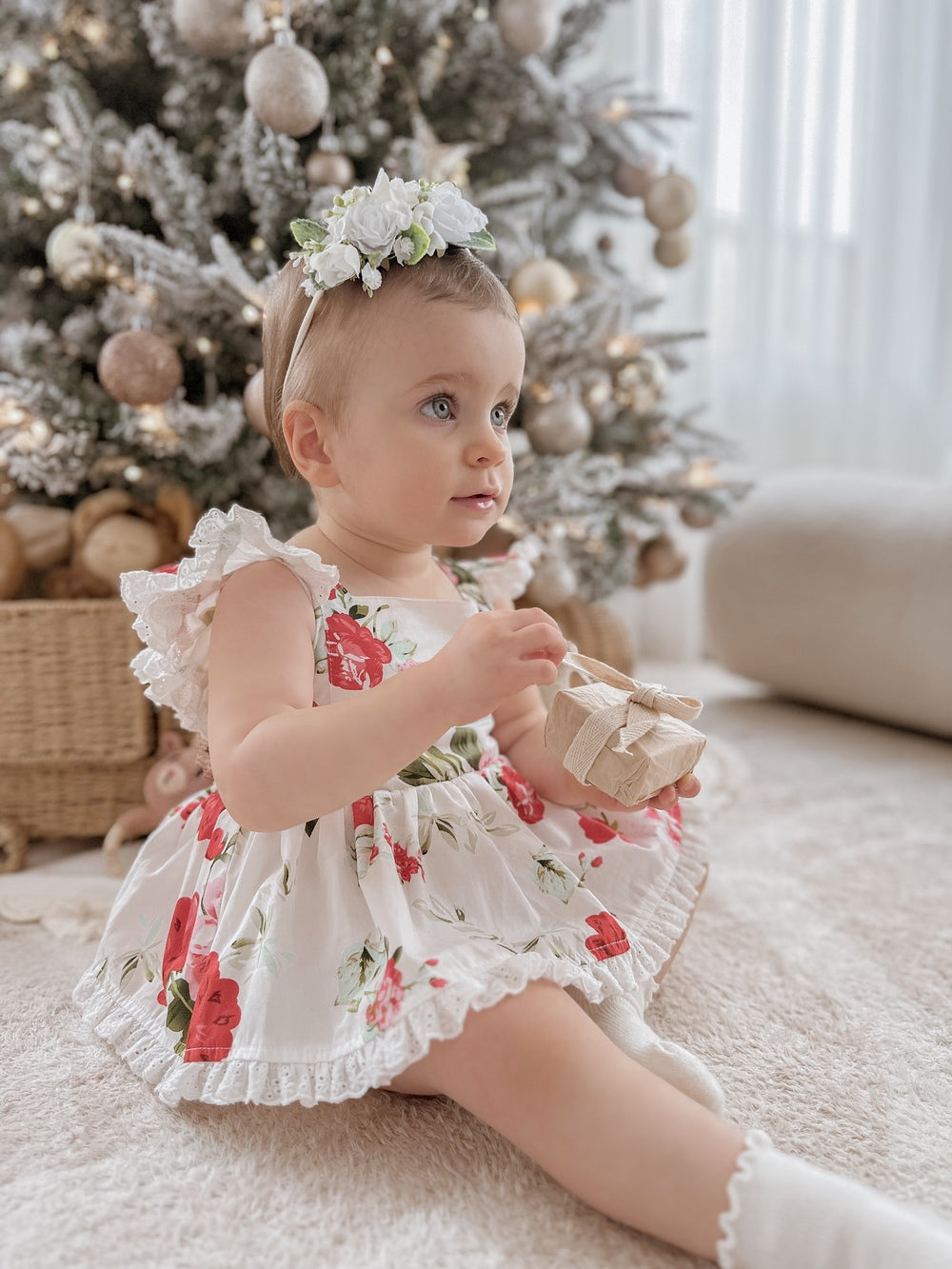 Baby in Faith Floral Romper holding Christmas present during holiday photos