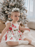 Baby girl wearing Faith Floral Christmas Romper with red and green florals sitting by the Christmas tree