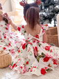 Sisters in matching Christmas floral dresses playing near presents and christmas tree