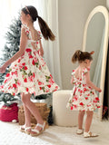 Older sister and younger sister wearing matching Faith Christmas Rose Dresses smiling by the Christmas tree
