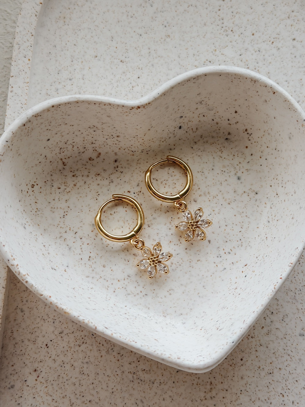 Flat lay of Flower Girls Gold Hoop Earrings – floral charm detail and polished finish