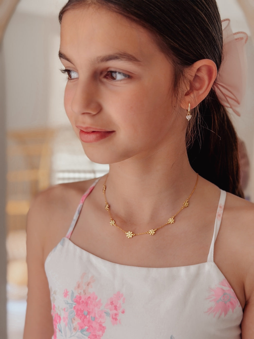 Girl wearing dainty gold daisy necklace for festive celebration