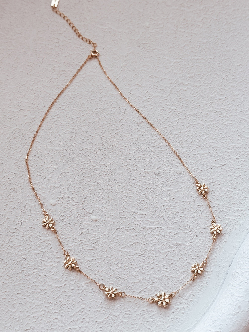 Close-up of daisy charm details on girls gold necklace