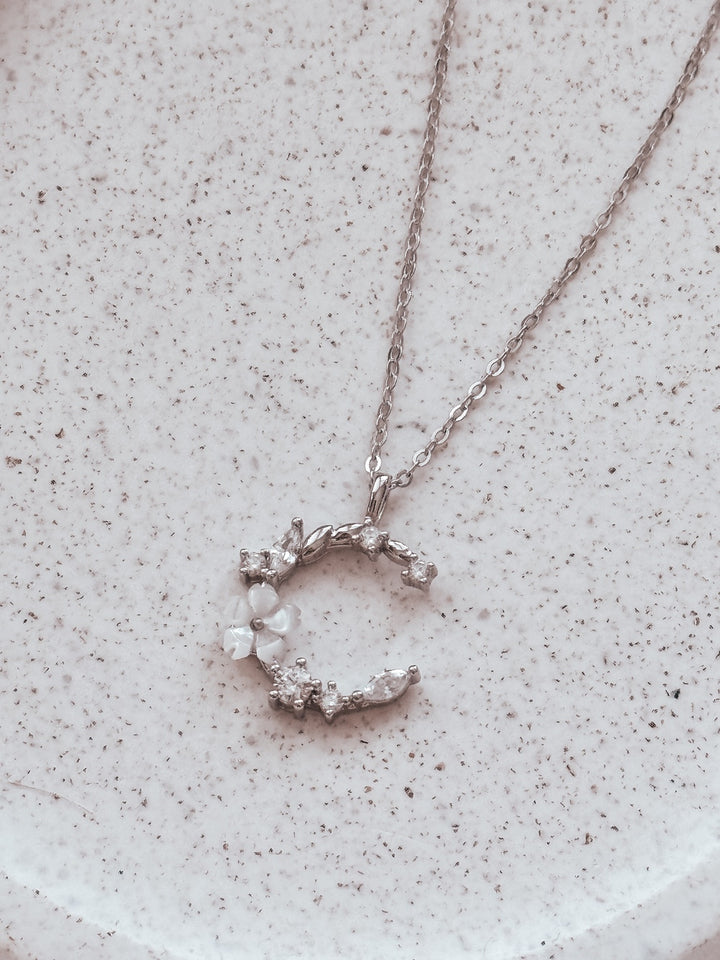 Sterling silver girls necklace with moon and floral detail on jewellery stand