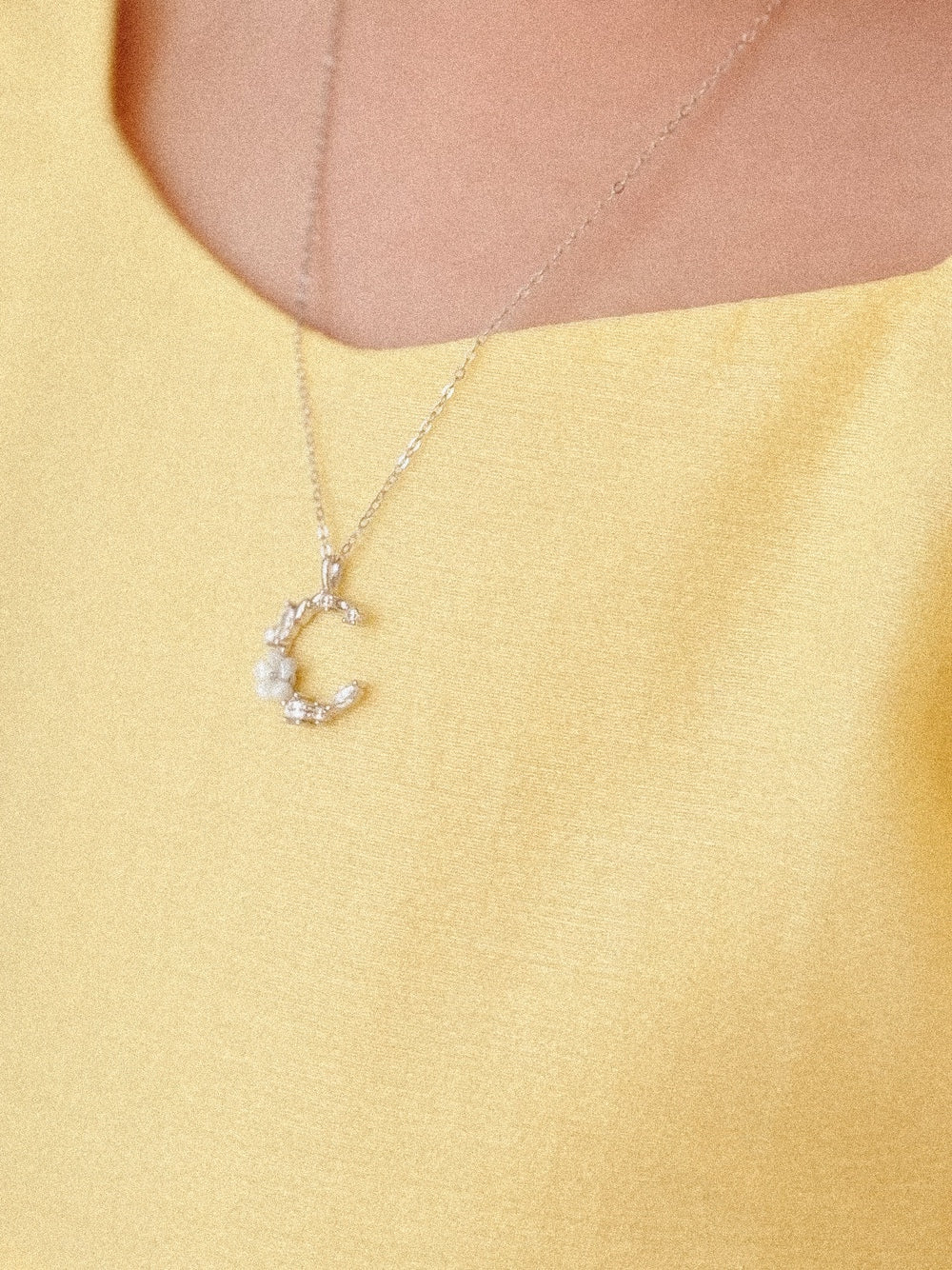Close-up of moon charm with diamantes and single white flower