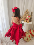 Child wearing red cotton festive dress sitting beside wrapped presents