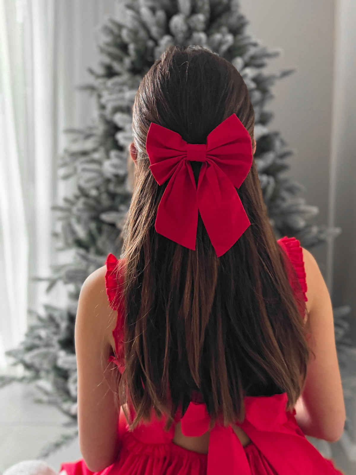 Medium red Christmas bow clipped into half-up hairstyle