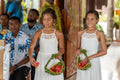 Two flower girls wearing white chiffon Isabelle Dresses walking down the aisle holding flowers