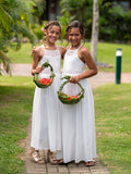Two flower girls standing outside in full-length white chiffon dresses during wedding photos