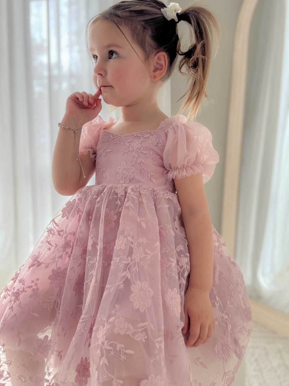 Girl wearing Isla Rose dusty pink flower girl dress from the front, sitting elegantly