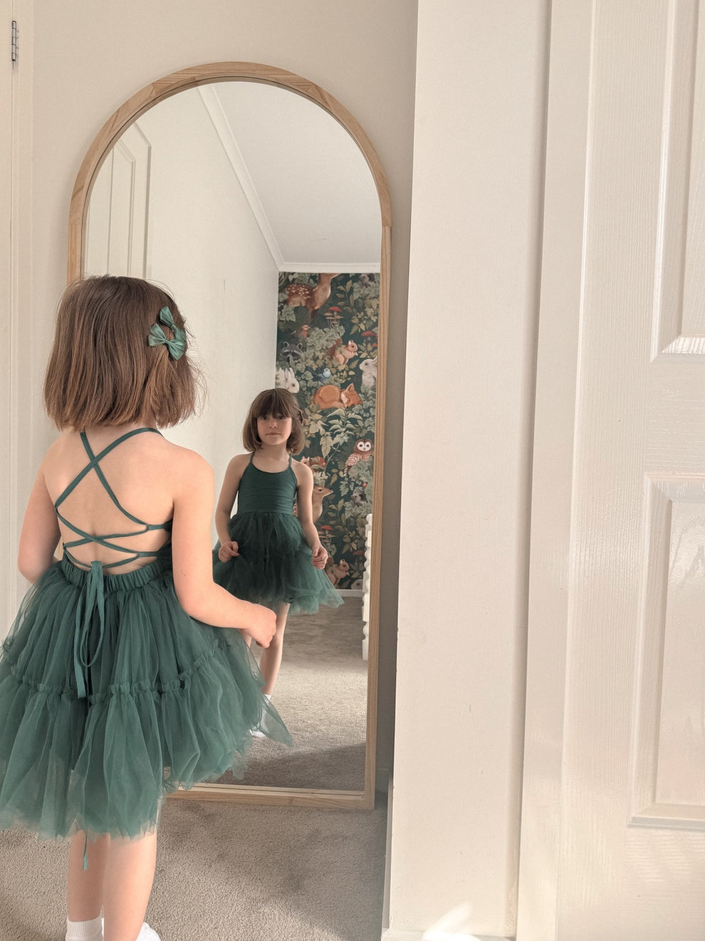 Juniper green Christmas dress reflected in a mirror, showing the front bodice and crisscross back.